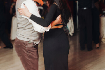 Couples dancing traditional latin argentinian dance milonga in the ballroom, tango salsa bachata kizomba lesson in red and purple lights, performance rehearsal, evening dance school class festival