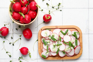 Board and bowl with fresh slices of radish on light tile background