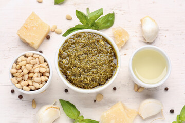 Composition with bowl of delicious pesto sauce and ingredients on white wooden table