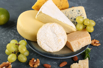 Fototapeta premium Plate with different types of cheese on green background