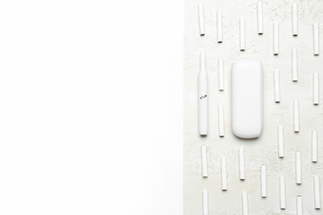 Composition with modern electronic cigar and many sticks on white table