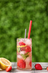 Glass of strawberry lemonade on grey tile table outdoors