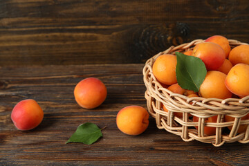 Wicker bowl with fresh apricots on wooden background
