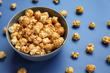Bowl with tasty popcorn on blue background