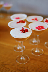 Several cocktail glasses filled with a light-colored drink, topped with a frothy layer