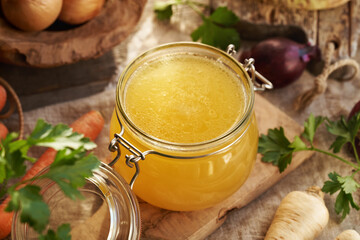 Bone broth in a glass jar with fresh vegetables