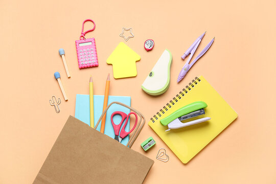 Composition with paper bag with various stationery on color background