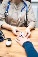 Nurse checks patient vitals in clinic. Medical professional measures patient's pulse and vitals...