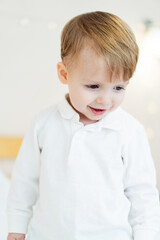 Toddler in white shirt playing. A joyful toddler dressed in a white shirt explores a bright and cozy indoor space with a playful demeanor.