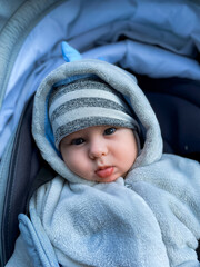 Baby in winter stroller outside. A baby in a cozy winter outfit sits in a stroller, surrounded by cool weather. The baby looks curious and content.