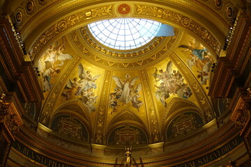 A beautiful golden fresco painting with Christian imagery graces the ceiling under the Gothic dome of St. Stephen's Basilica in Budapest, Hungary