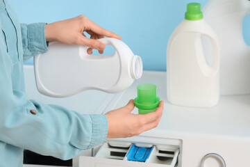 Woman pouring laundry detergent into washing machine, closeup