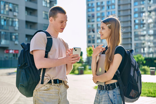 Young teenage guy and girl looking at smartphone together, urban background