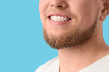 Fototapeta premium Smiling young bearded man on blue background, closeup