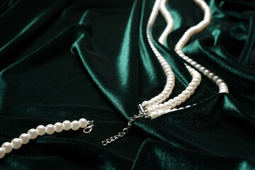 Fototapeta premium Beautiful pearl necklace on green cloth, closeup