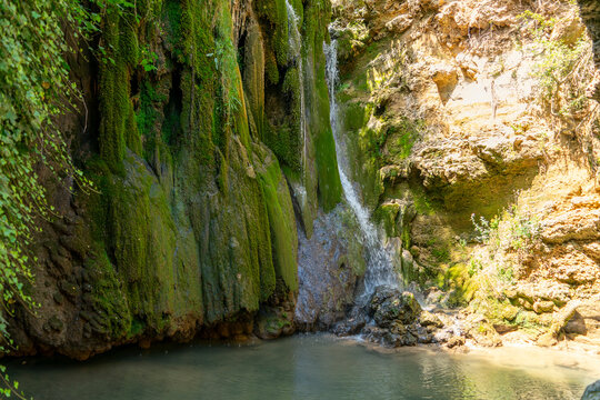 Beautiful view of a waterfall cascading over moss-covered rock walls in the Cuenca region, Spain