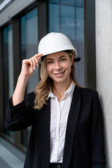 Pretty blonde young woman in hard cap smiling nicely and looking contented