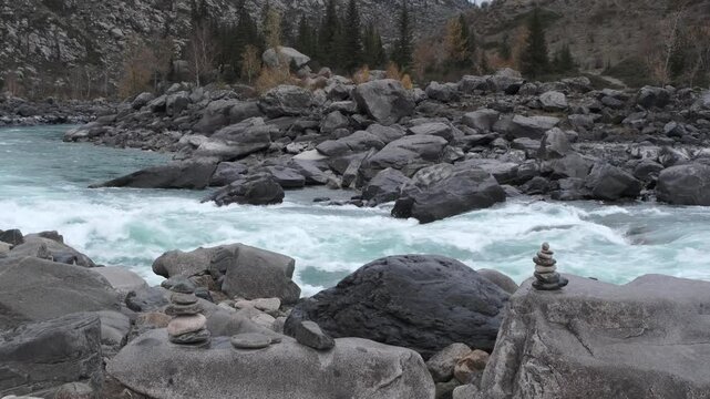 Fast-moving stream of seething mountain river runs along frozen stone banks. Amazing highland landscape with autumn bare grey forest at sunset. Ilgumen threshold, Katun river, Altai. Slow motion