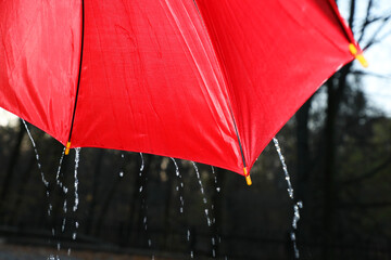 Open red umbrella under pouring rain outdoors, closeup