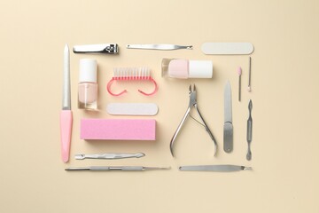 Set of pedicure tools on beige background, flat lay