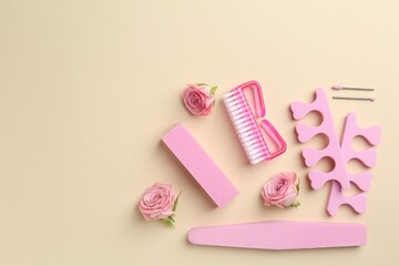 Set of pedicure tools and flowers on beige background, flat lay. Space for text