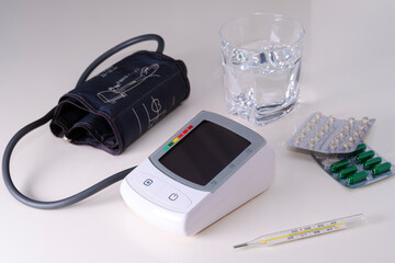 Kit for home health monitoring: tonometer, tablets, thermometer, glass of water.