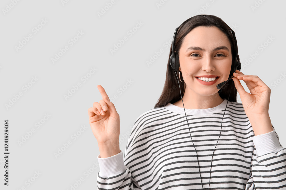 Poster female technical support agent in headset pointing at something on grey background