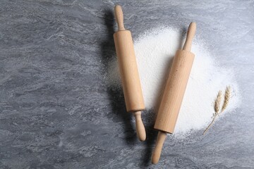 Rolling pins, flour and spikes on grey textured table, flat lay. Space for text
