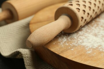 Wooden rolling pin, board and flour on table, closeup
