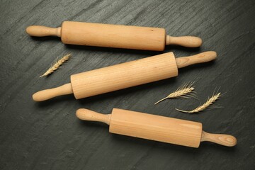 Wooden rolling pins and spikes on dark gray textured table, flat lay