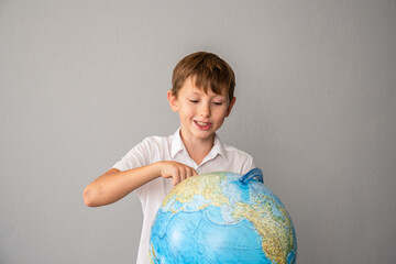 Boy Globe Education - Happy young boy pointing at globe, exploring the world, learning geography in a classroom or home setting.