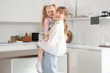 Nanny holding little girl in kitchen