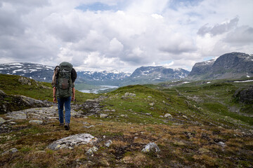 Hiking male carrying a large backpack s\walking in a scenic mountain landscape