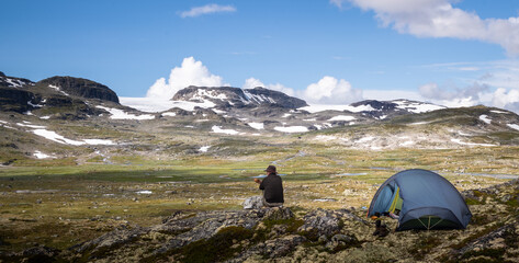 Hiking male sitting outside his tent in a spectacular mountain environment