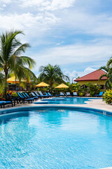 Obraz premium a swimming pool at an all-inclusive resort in the Caribbean, clear blue water, sun loungers, tropical plants