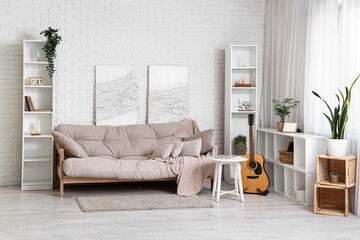 Beautiful interior of white living room with comfortable sofa, shelving units and houseplant