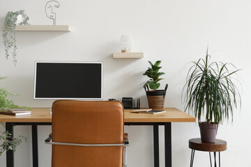 Modern workplace with computer monitor and houseplants near light wall in office