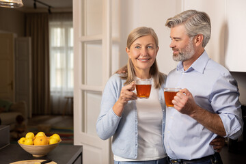 Happy elderly man and woman smiling while sharing healthy breakfast with tea at home