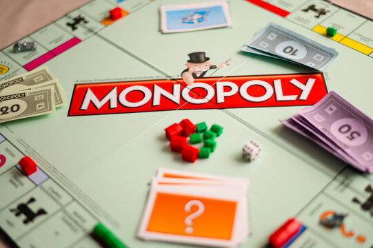 Monopoly Game Close-Up. Focus on Mr. Monopoly Logo with Dice Roll, Colorful Houses, and Play Money Scattered on the Game Board