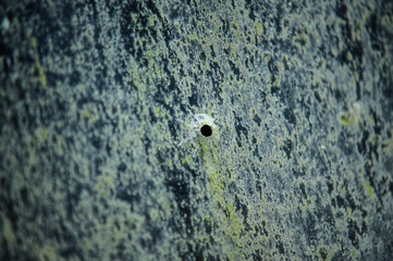 bullet hole in weathered metal surface.