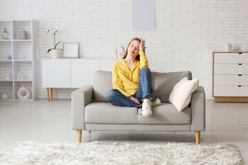 Obraz premium Young woman relaxing on sofa in living room