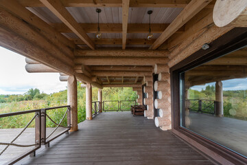 A Russian bathhouse made of solid logs and decking at the entrance in a picturesque place by the river.