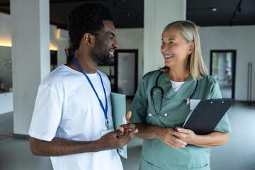 Female doctor in medical scrubs with an african american intern in the clinic