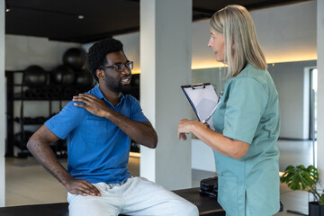 Female physical therapist talking to male patient and making notes