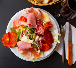 Plate of delicious Catalan salad of smoked sausage, ham, lettuce, bell pepper, tomatoes, cheese and chopped onions.....