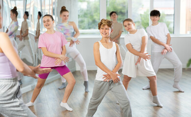 Obraz premium Young girls and boys repeat the movements of dance teacher, training in a spacious studio