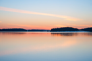 Early summer night by a calm lake in Finland with fog rising from the water
