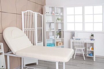 Interior of medical office with couch, doctor's workplace and folding screen