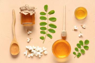 Jar and bowls of sweet honey with acacia flowers on beige background