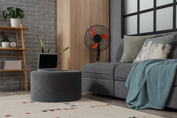 Electric fan and laptop on floor at home